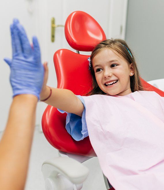 Little girl giving dentist high five during children's dentistry visit