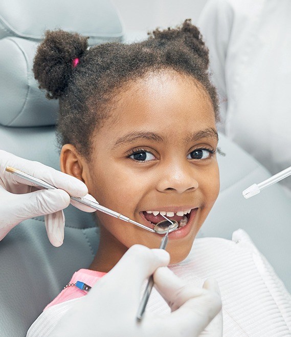 Dentist examining child's smile after pulp therapy