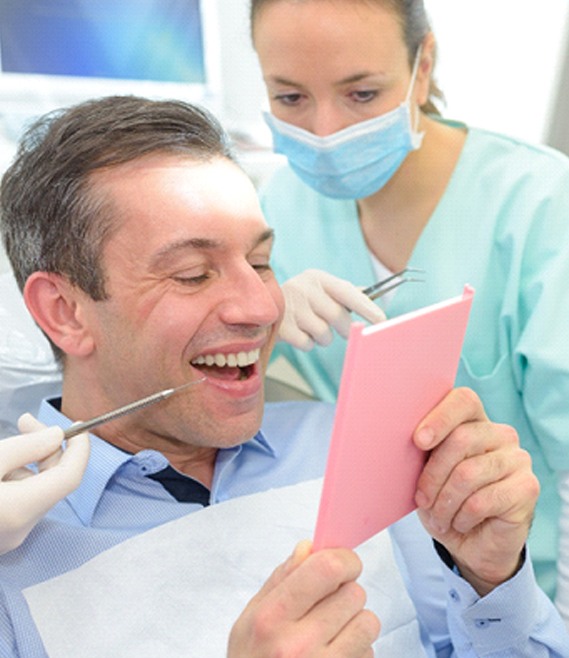 Patient looking at dental crown in dentist's mirror