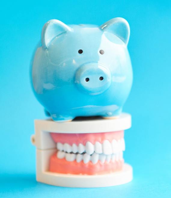 A blue piggy bank sitting on mock dentures