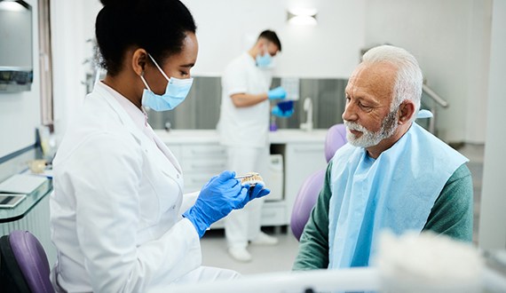 A dentist showing dentures to a patient