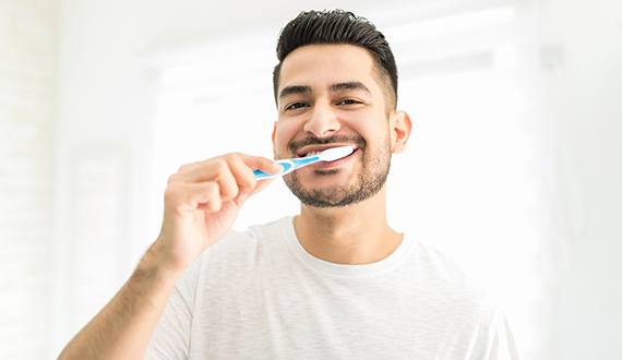 Man smiling while brushing teeth