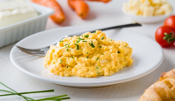 a plate with scrambled eggs and other foods around it