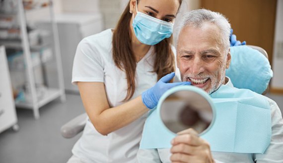 a patient checking his smile with a mirror