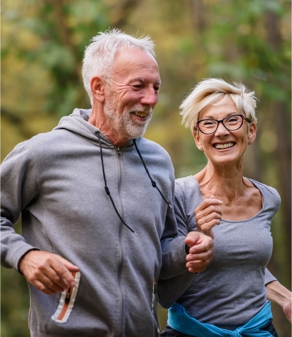 Man and woman jogging together after dental implant tooth replacement