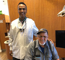 Panama City dentist smiling with senior man in dental chair