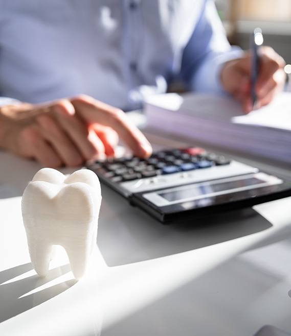 Person calculating dental insurance coverage using a calculator