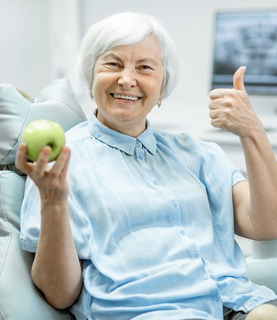 Woman holding an apple and giving a thumbs up