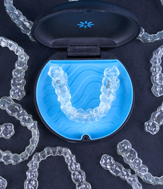 Invisalign aligners scattered around a single Invisalign tray in a protective case