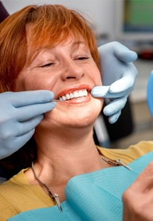 woman smiling while looking in dental mirror 