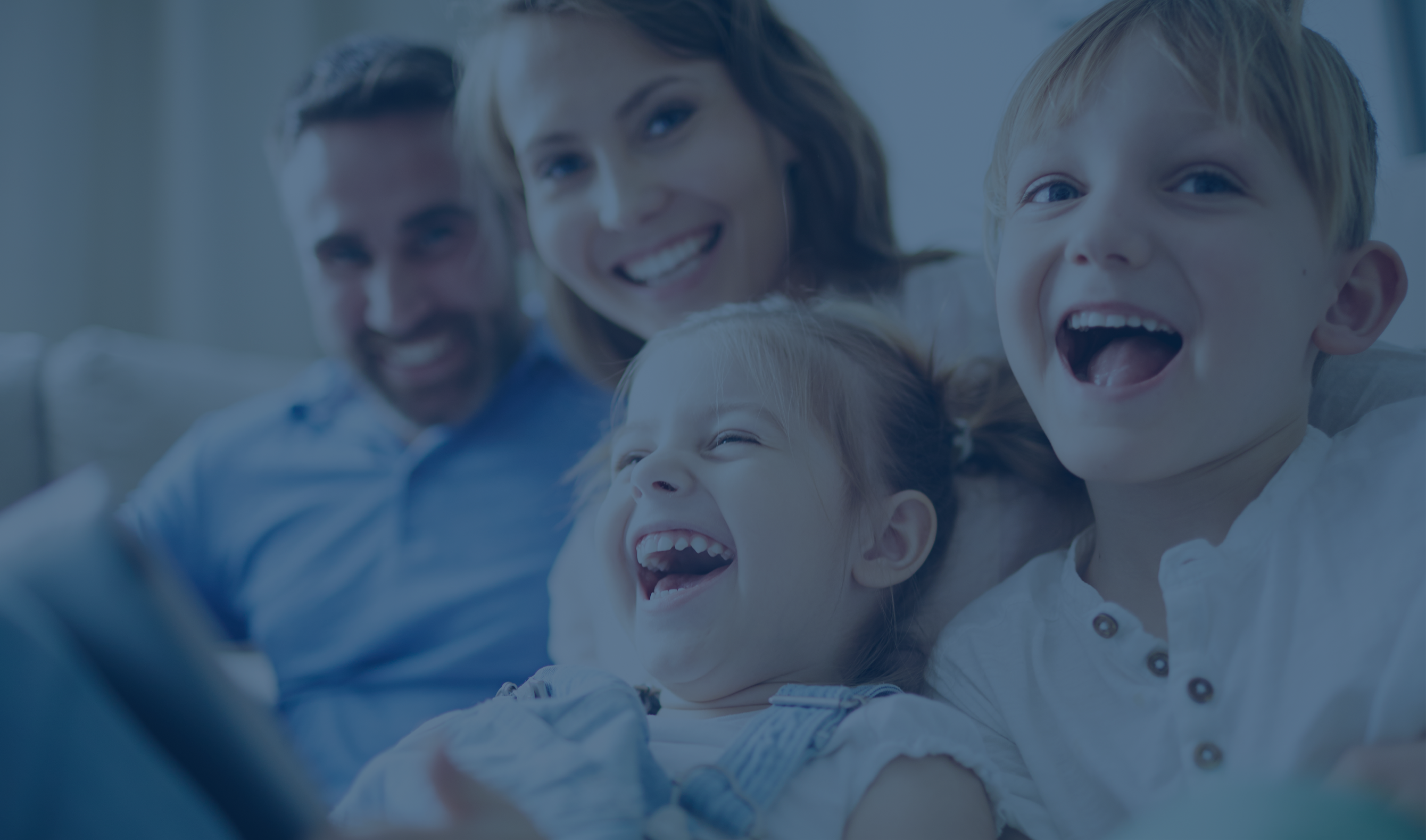 A family of four sits on a couch reflecting a cheerful atmospher.