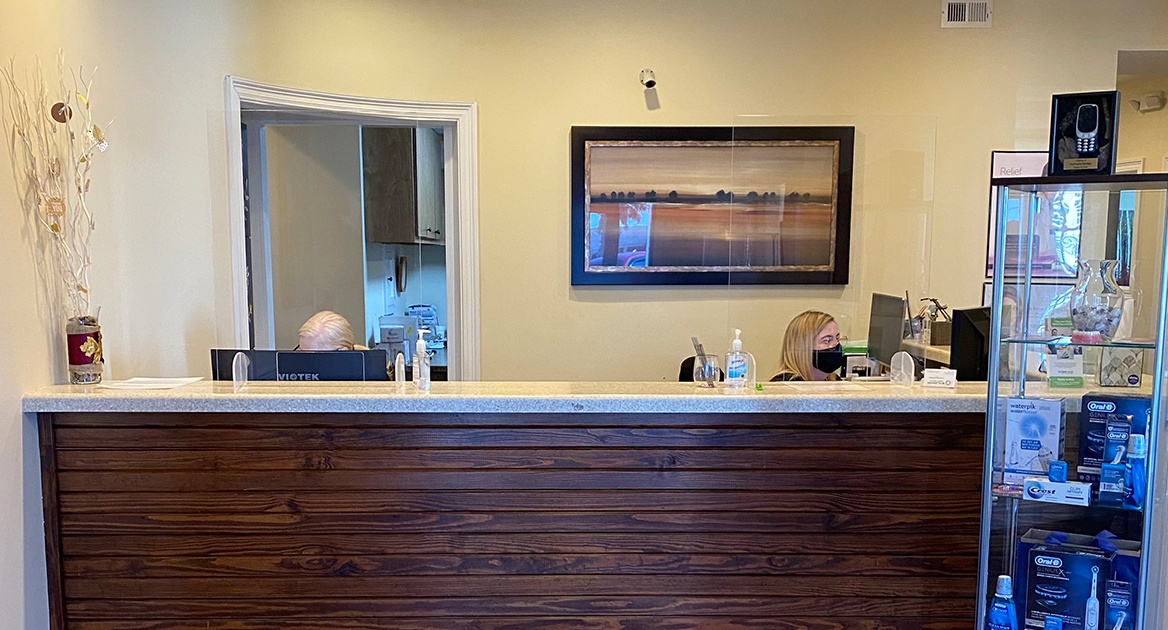 Two dental team members behind dental office reception desk