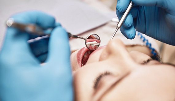 Dentist inspecting a patient’s teeth with dental mirror