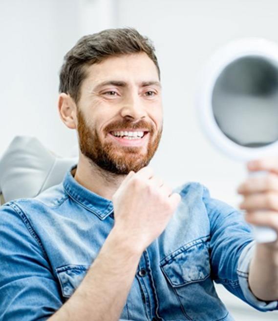 dental patient seeing his new and improved teeth in a mirror 