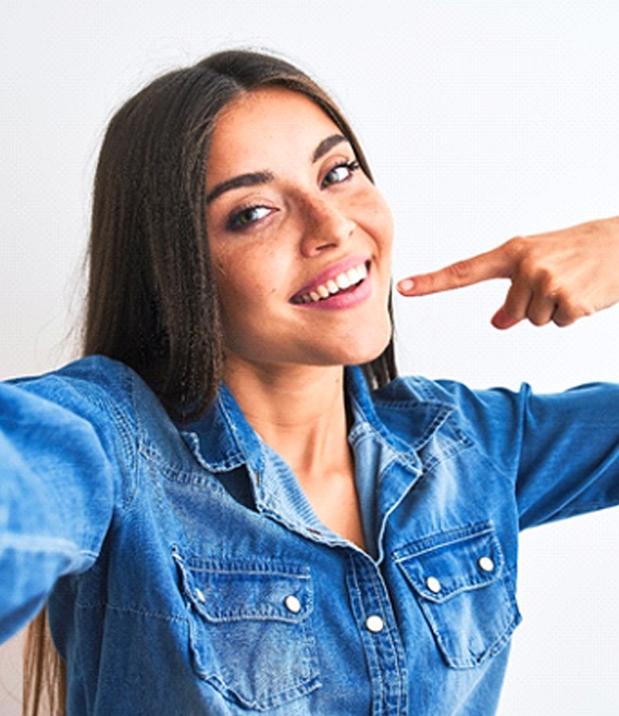 Woman pointing to her white, straight teeth in selfie