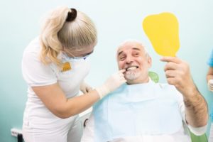 mature man in dental chair looking in mirror