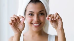 A woman holding up a strand of dental floss.