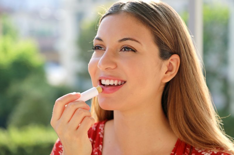 Woman smiling while applying lip balm