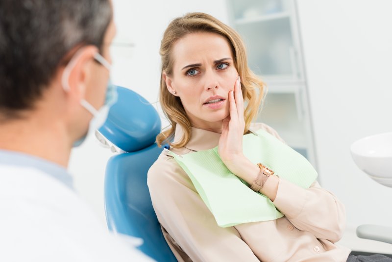 Patient holding their cheek due to tooth pain